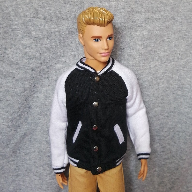 K&ouml;nnte beinhalten: Eine schwarze und wei&szlig;e Collegejacke mit Knopfleiste. Die Jacke hat wei&szlig;e &Auml;rmel und einen schwarzen K&ouml;rper mit gerippter Struktur.