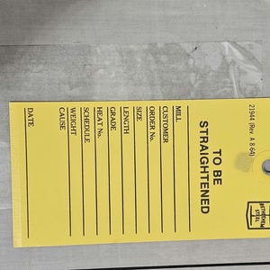 May include: A yellow tag with the text "TO BE STRAIGHTENED" in black. The tag includes fields for details like date, cause, weight, and order number. The tag also has the Bethlehem Steel logo and the text "21944 (Rev. A 8-64)."