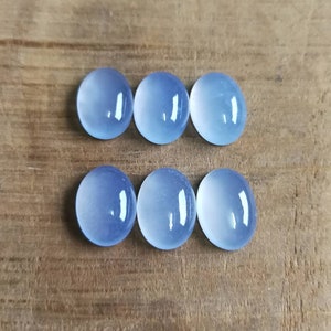Może przedstawiać: Sześć okrągłych, jasnoniebieskich kamieni szlachetnych w szlifie kaboszonowym na drewnianej powierzchni.