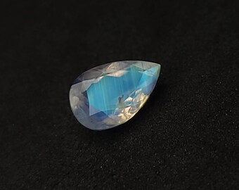 May include: A pear-shaped moonstone gemstone with a blue iridescent sheen.