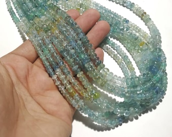 May include: A strand of light blue aquamarine beads, with some beads having a greenish hue. The beads are round and have a slightly irregular shape. The beads are strung on a clear thread.