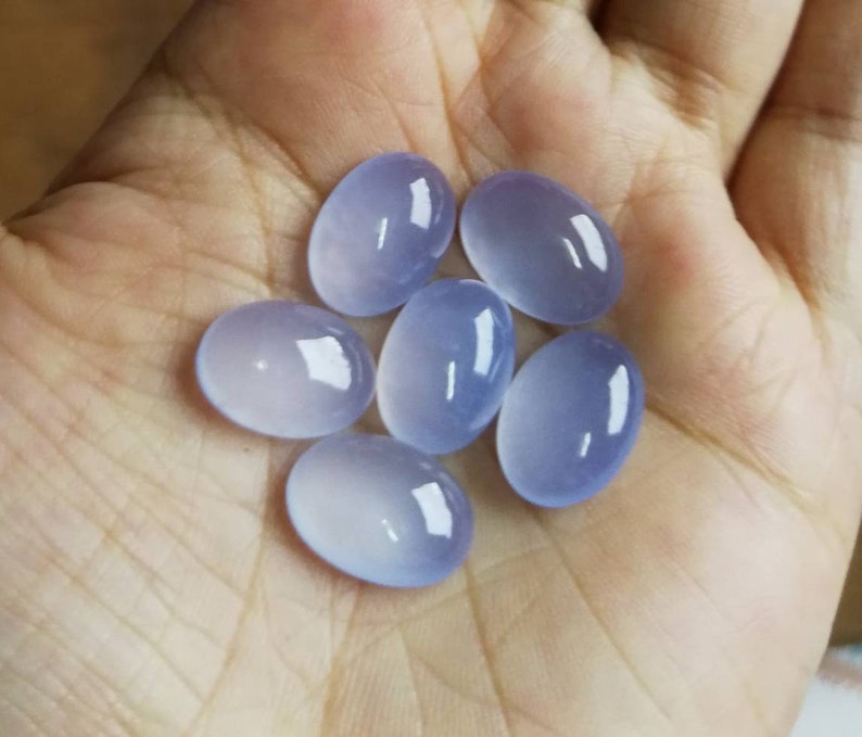 Może przedstawiać: Sześć owalnych, p&oacute;łprzezroczystych, jasnoniebieskich kamieni szlachetnych. Kamienie szlachetne są gładkie i wypolerowane.