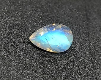 May include: A pearlescent teardrop-shaped gemstone with a blue iridescent sheen.