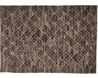 May include: A brown and beige area rug with a geometric diamond pattern. The rug has a woven texture and a subtle sheen.