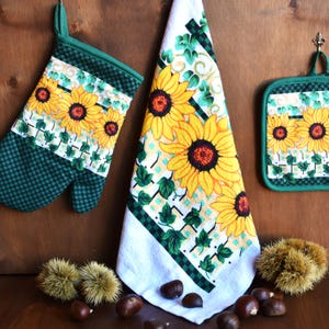 Puede incluir: Un juego de accesorios de cocina con un patrón a cuadros verde y blanco con girasoles y hiedra. El juego incluye un posavasos, un guante para horno y un paño de cocina.