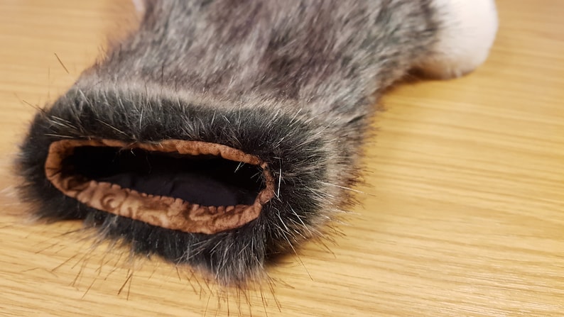 K&ouml;nnte beinhalten: Nahaufnahme des Innenbereichs einer grauen und schwarzen Kunstfellmanschette. Die Manschette hat ein braunes Stofffutter mit einem dekorativen Muster.