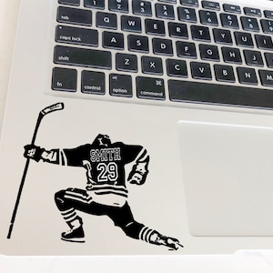 May include: Black and white silhouette of a hockey player in a skating pose, holding a hockey stick. The player is wearing a jersey with the name "SMITH" and the number "29" on the back.