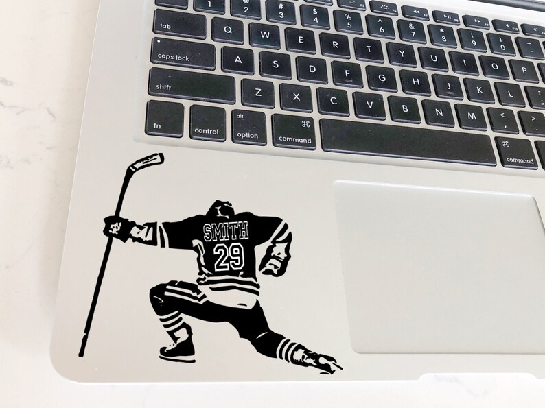 May include: Black and white silhouette of a hockey player in a skating pose, holding a hockey stick. The player is wearing a jersey with the name "SMITH" and the number "29" on the back.