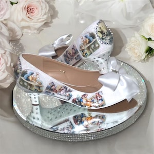 May include: White satin bridal shoes with a glitter finish and a white satin bow. The shoes feature a print of characters from Alice in Wonderland.
