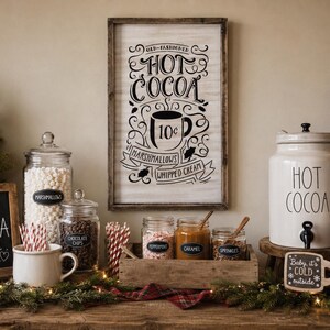 May include: A rectangular wooden sign with black text reading Old-Fashioned Hot Cocoa, 10 cents, Marshmallows, and Whipped Cream. The sign features a central mug illustration and is displayed alongside glass jars, a ceramic dispenser, and mugs.