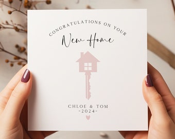 May include: A white card with the text "Congratulations on your New Home" in black script font. A pink house key icon is below the text. The names "Chloe & Tom" and the year "2024" are printed below the icon.