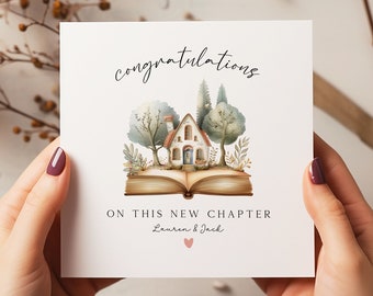 May include: A white card with a watercolor illustration of a house on an open book. The text reads "congratulations on this new chapter Lauren & Jack" with a pink heart.