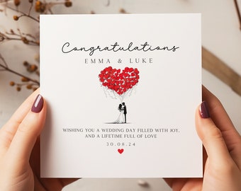 May include: A white card with black text that reads "Congratulations Emma & Luke" and "Wishing you a wedding day filled with joy, and a lifetime full of love 30.08.24". A black and white illustration of a bride and groom standing under a heart-shaped balloon made of red hearts.