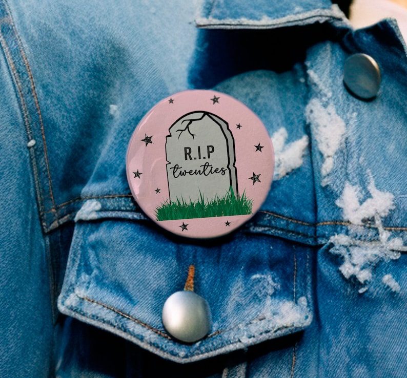 May include: A pink button with a tombstone graphic and the text "R.I.P. twenties" surrounded by stars.
