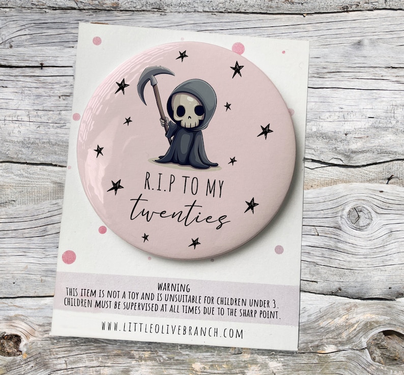 May include: A pink round mirror with a cartoon image of the Grim Reaper holding a scythe. The mirror has a white border and the text "R.I.P TO MY twenties" in black. The background of the mirror is pink with white stars.