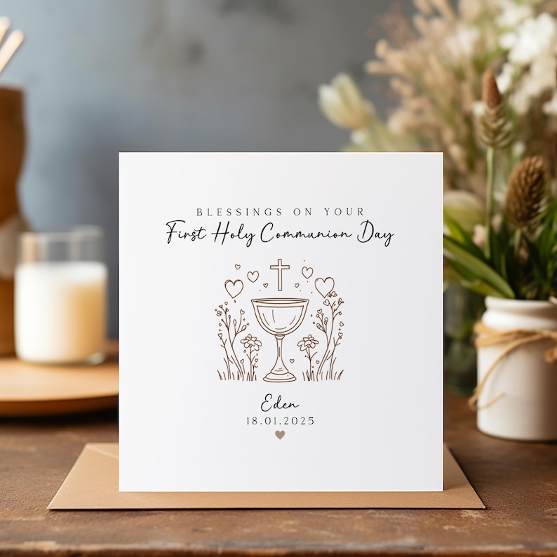 May include: A white card with a brown outline of a chalice with a cross on top, surrounded by hearts and flowers. The text "Blessings on your First Holy Communion Day" is at the top of the card. The name "Eden" and the date "18.01.2025" are at the bottom of the card.