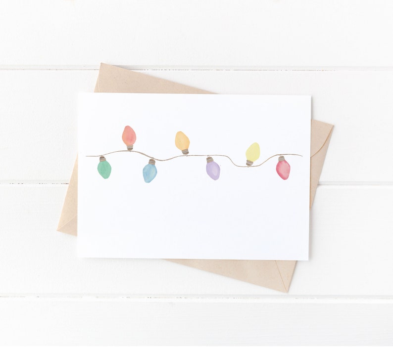 Op de afbeelding: Een witte kaart met een string van kleurrijke lampjes die erop getekend zijn. De lampjes zijn rood, oranje, geel, groen, blauw, paars en roze.