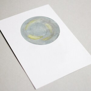 May include: A watercolor painting of a gray and yellow circle on a white background.