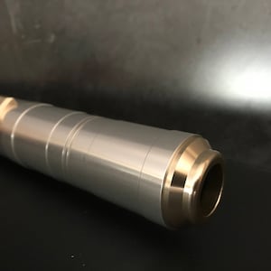 May include: A silver lightsaber with a gold-colored tip and a red button on the side.