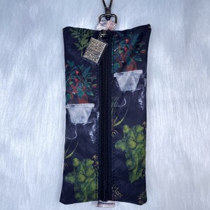 May include: A black zippered pouch with a silver key ring. The pouch has a floral print with green leaves and red flowers. The zipper is black and the key ring is silver.