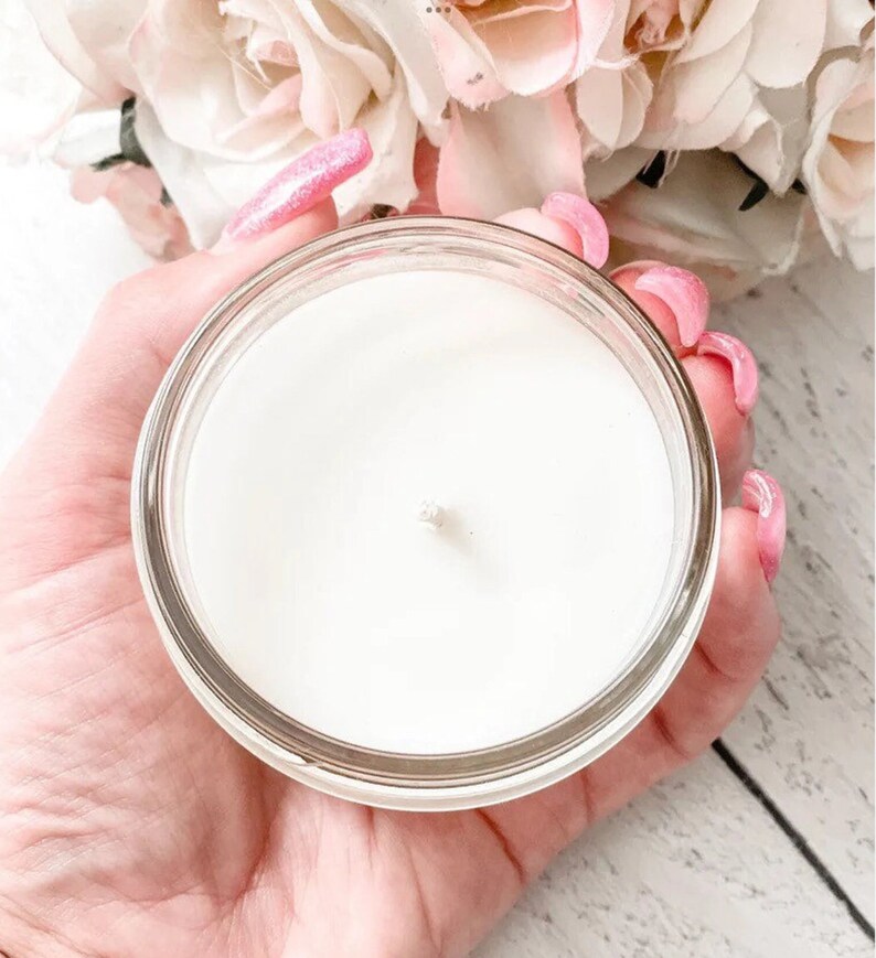 a person holding a glass jar with a candle in it