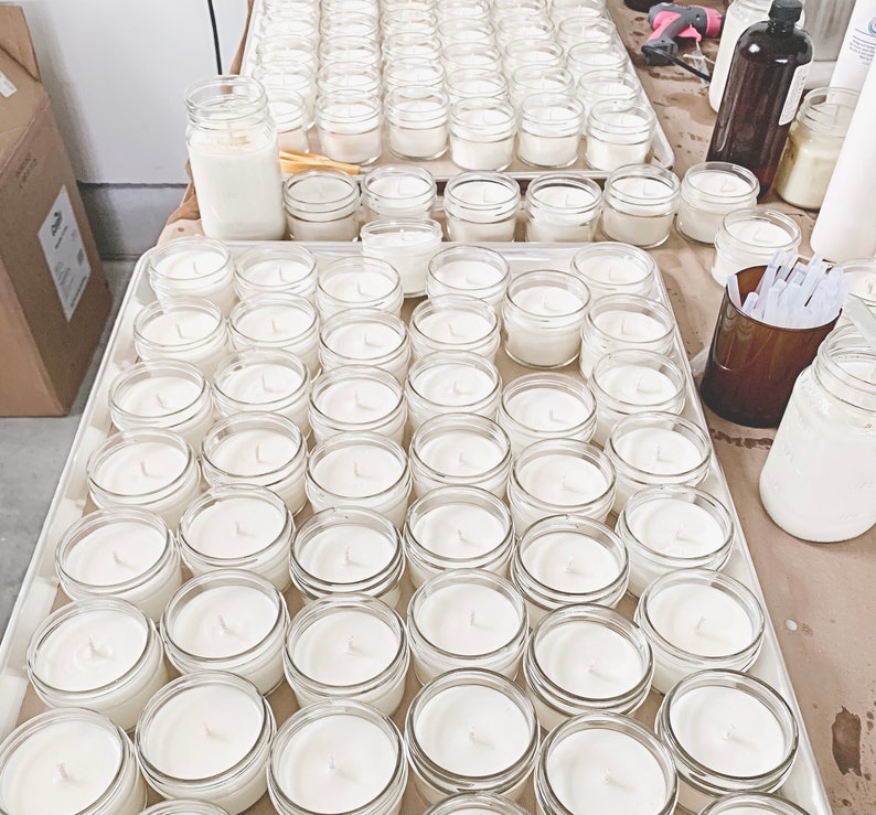 a table topped with lots of white jars filled with liquid