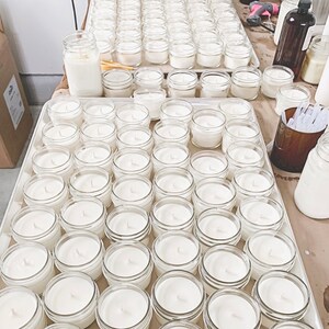 a table topped with lots of white jars filled with liquid