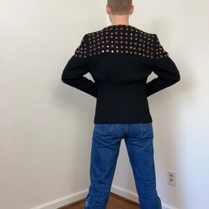 May include: A black blazer with a decorative pattern of gold and pink embellishments on the back.