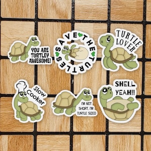 May include: Set of 7 turtle-themed stickers with various designs and sayings. The stickers feature green turtles with brown shells and white eyes. The sayings include "Save the Turtles", "You are Turtley Awesome", "Turtle Lover", "Slow Cooker", "I'm not short, I'm turtle sized", and "Shell Yeah!"
