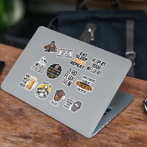 May include: A set of 11 welder themed stickers featuring various designs and sayings, including "I welded it, I welded it", "Will weld for beer", "Trust me I'm a welder", "Welders have bigger rods", "Zero flux given", "My thoughts are dirty but my welds are clean", "Welders do it in all positions", "Eat sleep weld repeat", "Respect your welders", and "I'm silently judging your welds". The stickers are on a silver laptop.