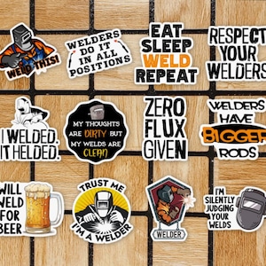 May include: A set of 12 colourful stickers with humorous sayings about welding. The stickers feature welding helmets, welding tools, and other welding-related imagery. The text on the stickers includes phrases like "Weld This!" and "Welders Have Bigger Rods".