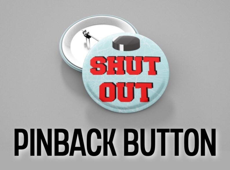 May include: A blue and white pinback button with a hockey puck on top and the text "SHUT OUT" in red.