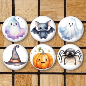 Peut inclure: Six boutons sur le thème d'Halloween avec des illustrations à l'aquarelle. Les boutons représentent un fantôme, une chauve-souris, une citrouille, une araignée, un chapeau de sorcière et un autre fantôme.