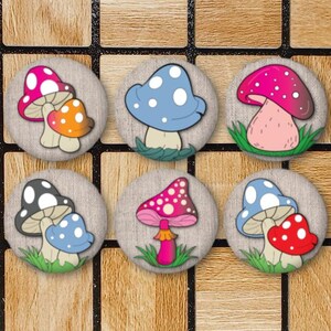 May include: Six round wooden buttons with mushroom designs. Each button features a different mushroom illustration in various colors, including pink, blue, and orange. The buttons are set against a wooden background with a grid pattern.