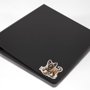 May include: Black binder with a sticker of a brown and black puppy on the front.