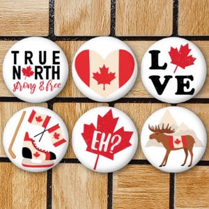 May include: Six round white buttons with different Canadian themed designs. The designs include a maple leaf, a hockey player, a moose, the words "True North Strong & Free", "Eh?" and "Love".