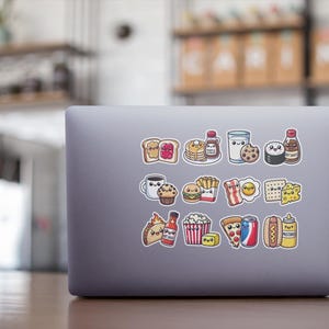 May include: A laptop computer with a variety of colorful stickers depicting cartoon food items, including a slice of pizza, a hot dog, a hamburger, a glass of milk, a donut, a cupcake, a piece of toast, a bottle of ketchup, a bottle of hot sauce, a bag of popcorn, a french fry, a piece of bacon, an egg, a piece of cheese, a piece of sushi, a bottle of syrup, and a glass of milk.