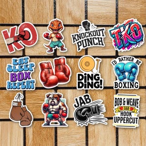 Peut inclure: Un ensemble de 10 autocollants colorés sur le thème de la boxe. Les autocollants présentent diverses phrases et images liées à la boxe, notamment un dinosaure, un bouledogue, des gants de boxe et une cloche. Les autocollants sont parfaits pour ajouter une touche de personnalité aux ordinateurs portables, aux bouteilles d'eau ou à d'autres surfaces.