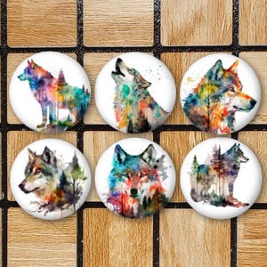 May include: Six round watercolor painted magnets featuring different wolf designs. Each magnet has a white background and features a wolf with a colourful watercolor design. The wolf designs include a wolf howling at the moon, a wolf with its head turned to the side, and a wolf standing in a forest.