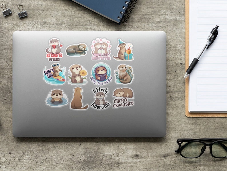 Op de afbeelding: Een set van 12 otter stickers met verschillende poses en spreuken. De stickers tonen otters in verschillende activiteiten, zoals surfen, zwemmen en een zonnebloem vasthouden. De spreuken op de stickers zijn "Wees aardig voor otters", "Surf's Up!" en "Otter-ly Exhausted".
