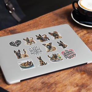 May include: A silver laptop computer with a variety of stickers featuring Belgian Malinois dogs. The stickers include images of the dogs, text that says "I love Belgian Malinois" and "My Belgian Malinois is Pawsome", and a heart with the words "Belgian Malinois".