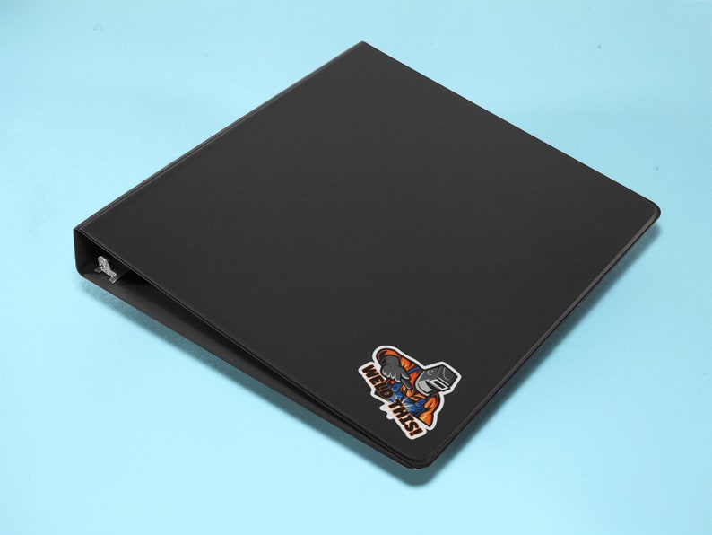 May include: Black binder with a sticker of a cartoon welder holding a welding torch and the text "Weld This!"