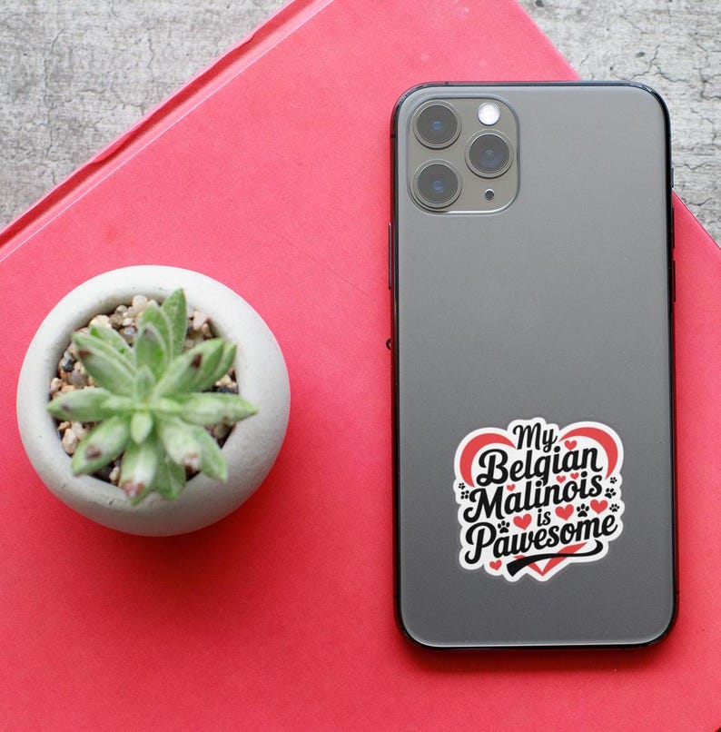 May include: A black iPhone with a white sticker that says "My Belgian Malinois is Pawsome" with a red heart and paw prints. The sticker is on the back of the phone.