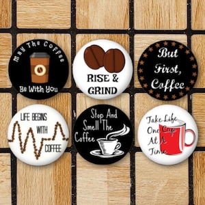 May include: Set of 8 round coffee themed buttons with various sayings. The buttons are white, black, and red with black text. The sayings include "May the Coffee Be With You", "Rise & Grind", "But First, Coffee", "Life Begins With Coffee", "Stop And Smell The Coffee", "Take Life One Cup At A Time", "Coffee", and "Coffee".