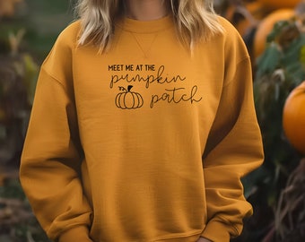 May include: Mustard yellow sweatshirt with the text "Meet Me at the Pumpkin Patch" in black script and a pumpkin graphic. The sweatshirt is a crew neck style.