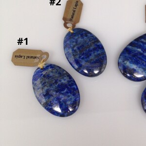 May include: Four oval and teardrop shaped lapis lazuli pendants with gold tags that say "Natural Lapis". The pendants are numbered 1 through 4.
