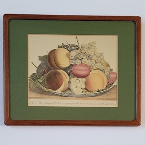 May include: A framed print of a still life featuring a bowl of fruit. The bowl contains peaches, plums, and grapes. The print is titled "A Paris chez Viquien N&deg; d'Estampes grande cours du Palais du Tribunat N&deg; 30".