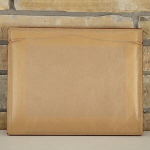 May include: A brown cardboard picture frame with a light brown backing.