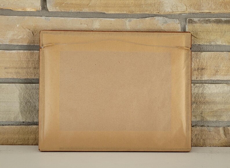 May include: A brown cardboard picture frame with a light brown backing.