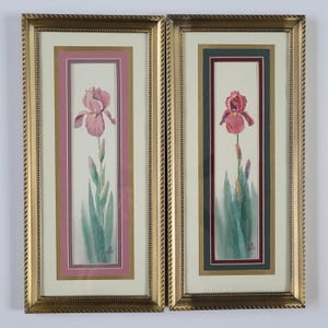 May include: Two framed watercolor paintings of pink and red iris flowers. The paintings are in gold frames with a double mat.